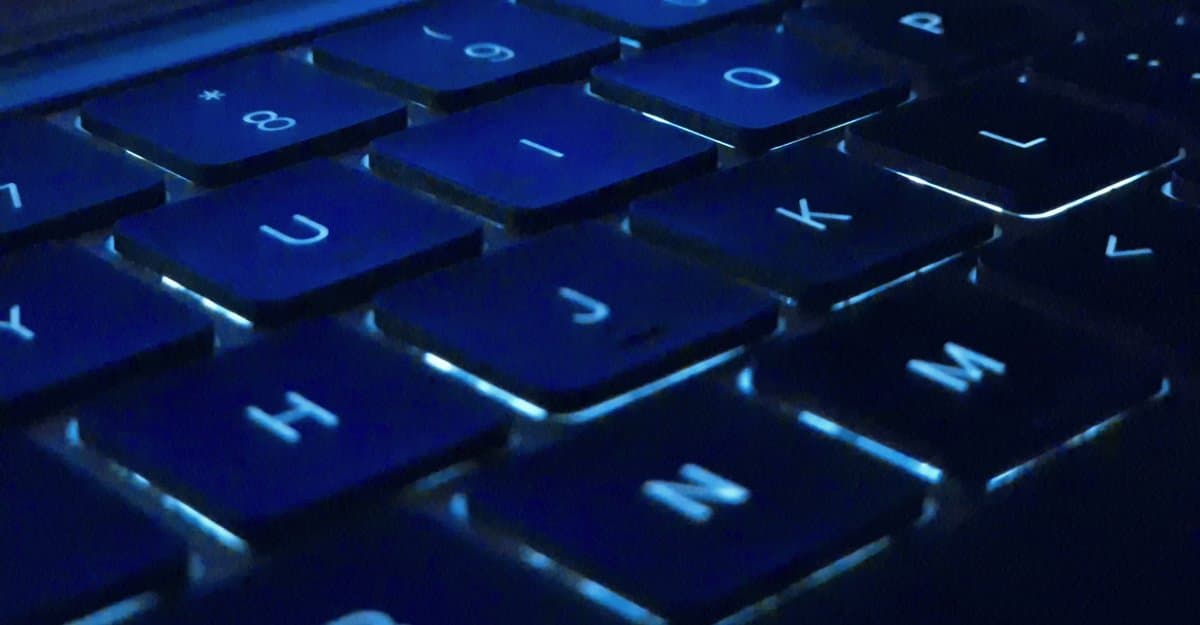 Close-up of backlit MacBook Pro keys glowing blue