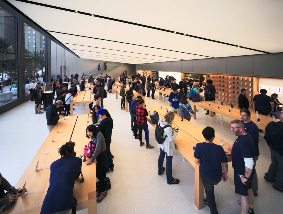 Apple Store interior with wood display tables and wall-mounted accessory displays